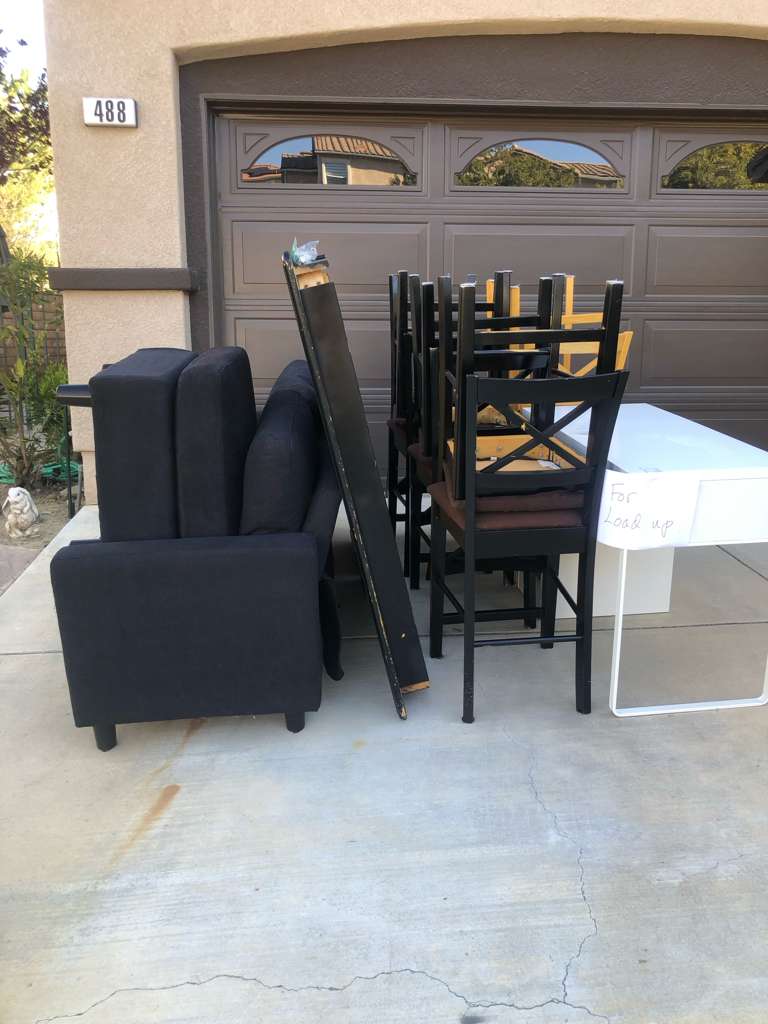 Curbside furniture pickup — sofa, chairs and desk staged in a driveway for junk removal Los Angeles